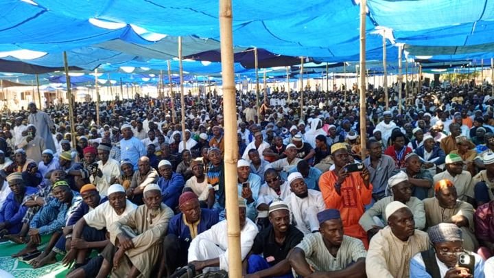 A large congregation seated under canopies